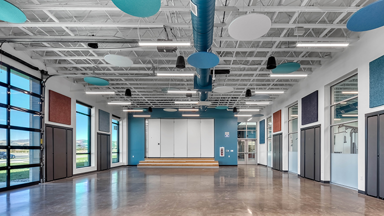 Large middle school performance and assembly space with blue and white accents and large windows