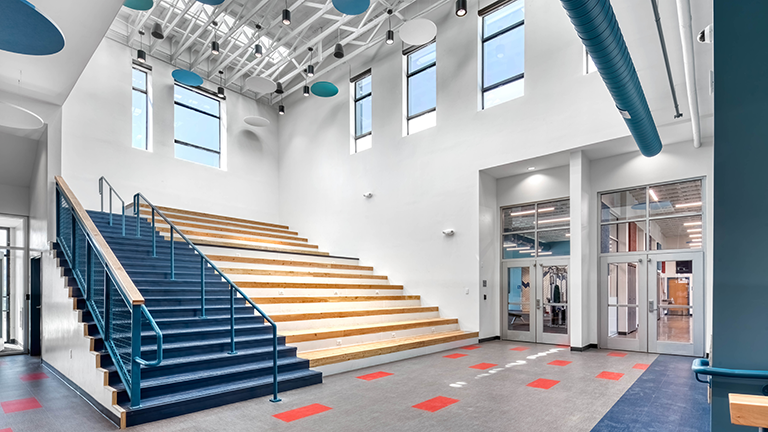 Middle school assembly and stair space with a lot of natural light and blue accents