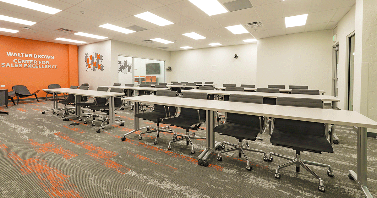 Modern college of business classroom containing rows of desks and chairs and orange accents