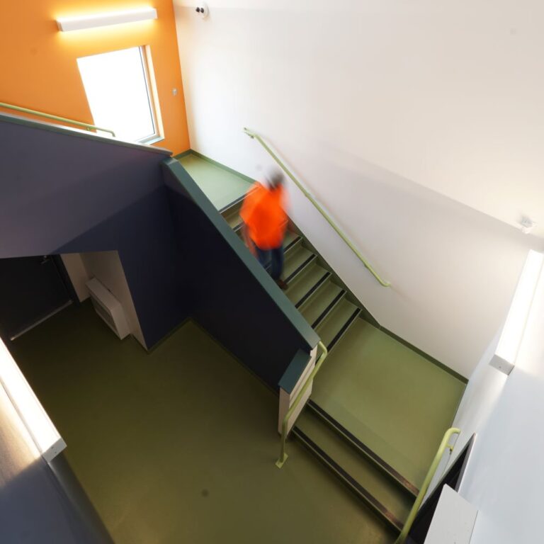Person walking down green stairway with orange walls