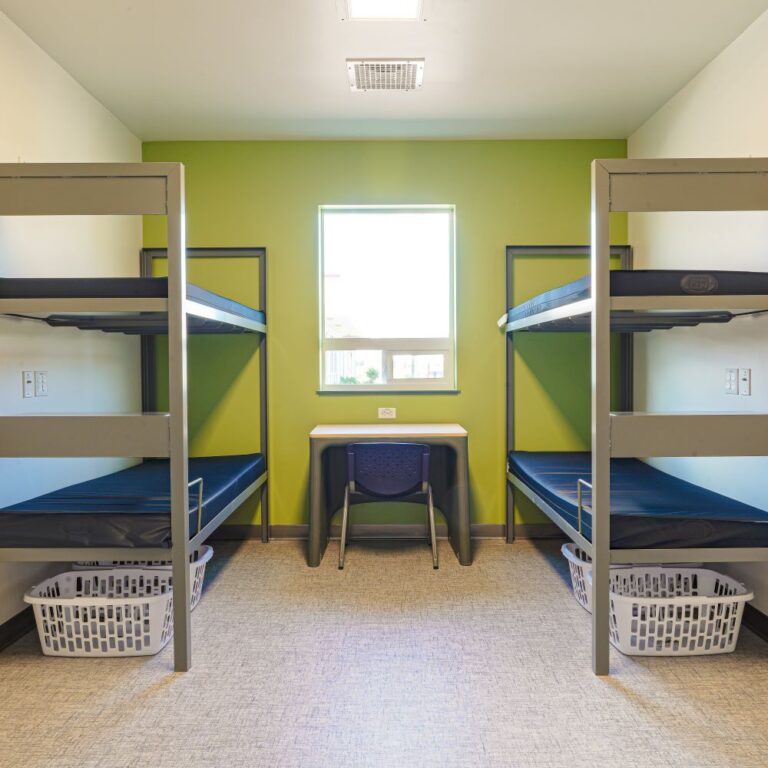 Dorm-style room with green walls, two bunks and a small desk